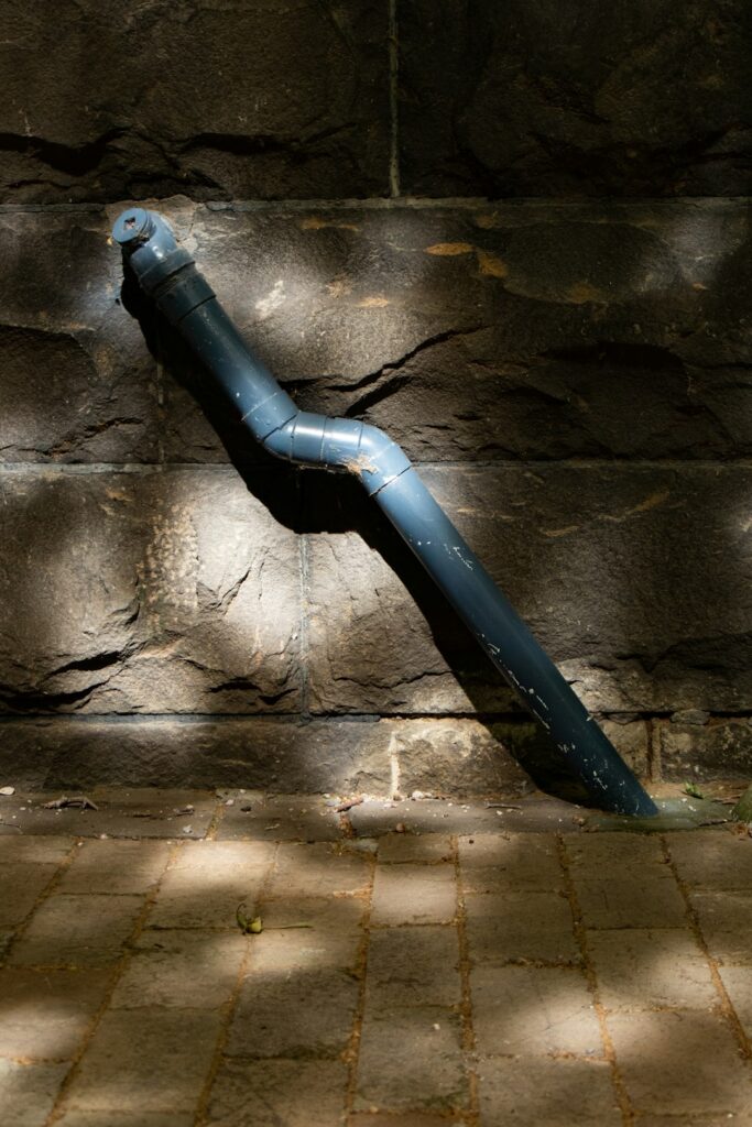 Rainwater flows through a residential gutter and downspout onto a splash block away from the foundation.